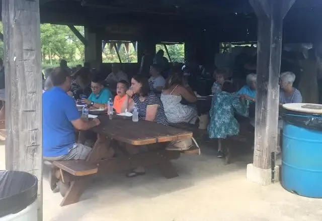 Families filling the picnic tables for a meal under the shelter