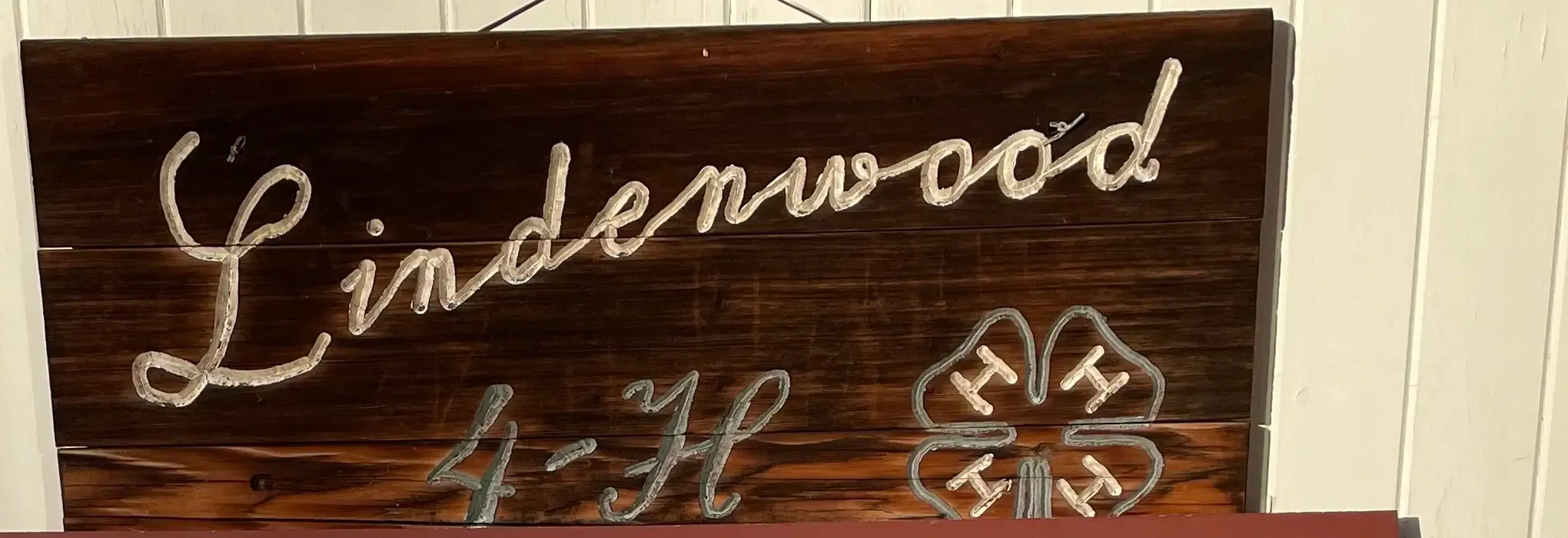 The hand-painted wooden Lindenwood 4-H sign with the four-leaf-clover 4-H emblem, hanging at the community center