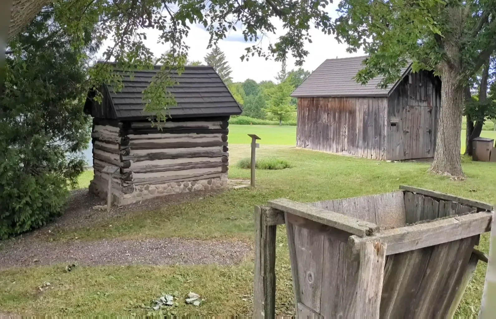 A panorama of the village yard, from a small chinked-log outbuilding to the weathered sheds beyond